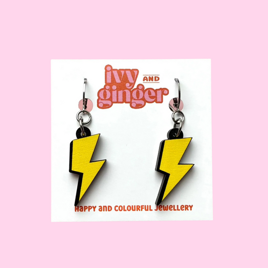 A photograph of two lightning bolt shaped dangle earrings connected to a small huggie hoop presented on a white earring card with the brand name 'ivy and ginger' at the top.