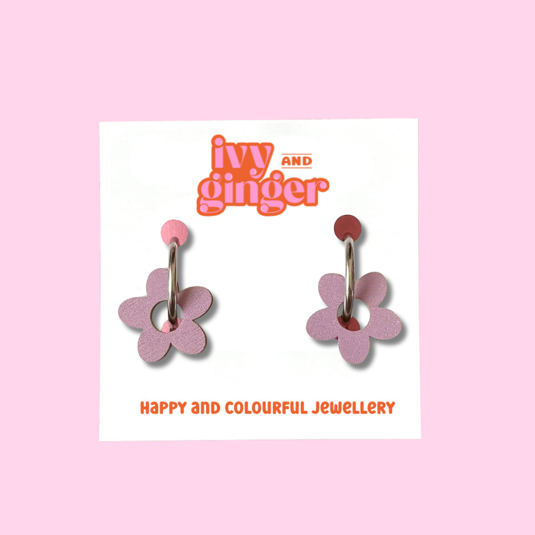 Dusky lilac coloured wooden flower shapes attached to a steel hoop presented on a white backing card with the brand name 'ivy and ginger' at the top.