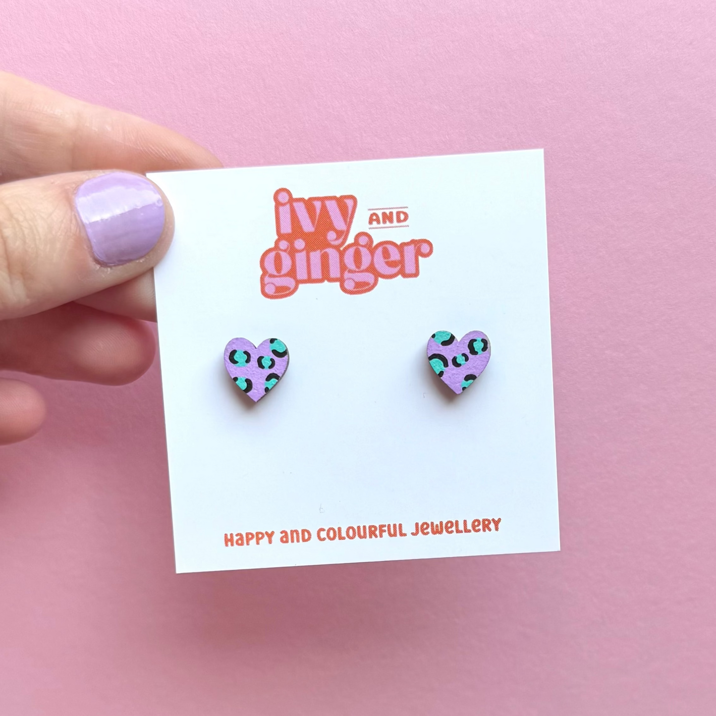Heart-shaped earrings on a 'ivy and ginger' branded card against a pink background