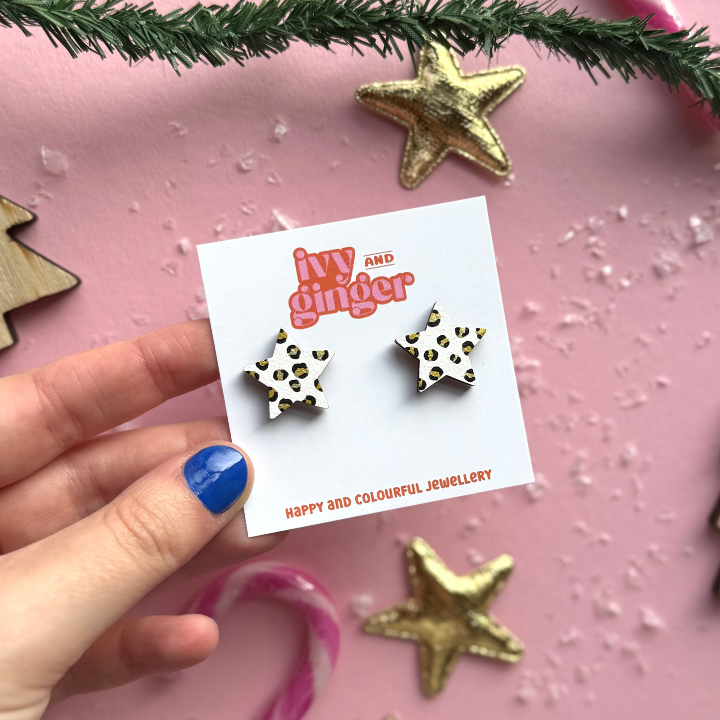 Star-shaped earrings on a 'ivy and ginger' card with decorative items on a pink background