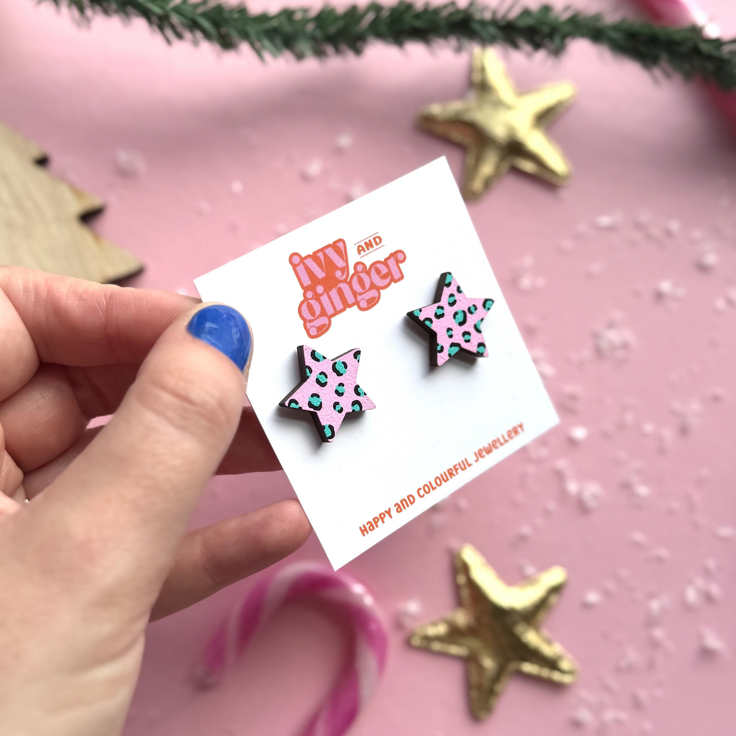Star-shaped earrings on a 'ivy and ginger' card with decorative background