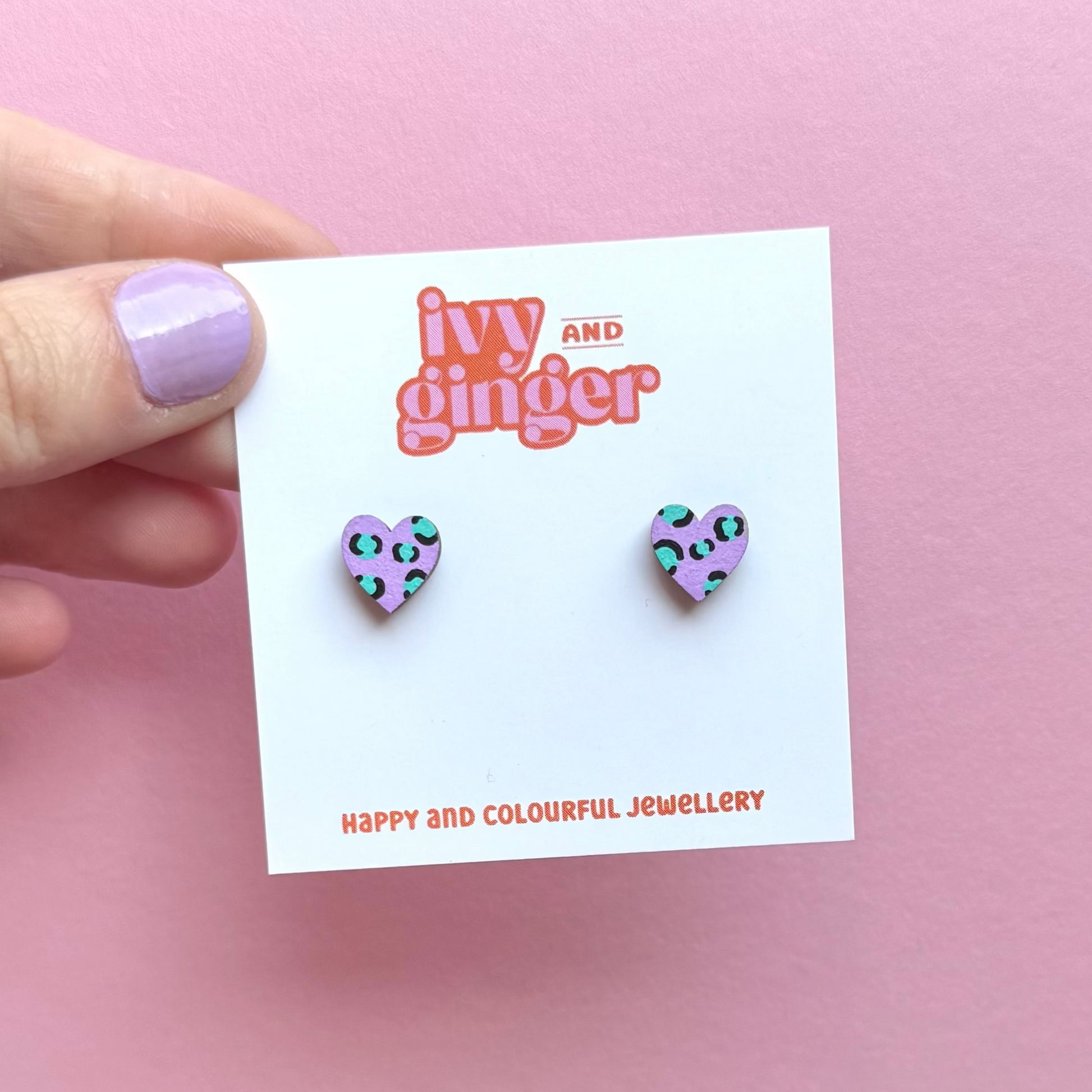 Heart-shaped earrings on a 'ivy and ginger' branded card against a pink background