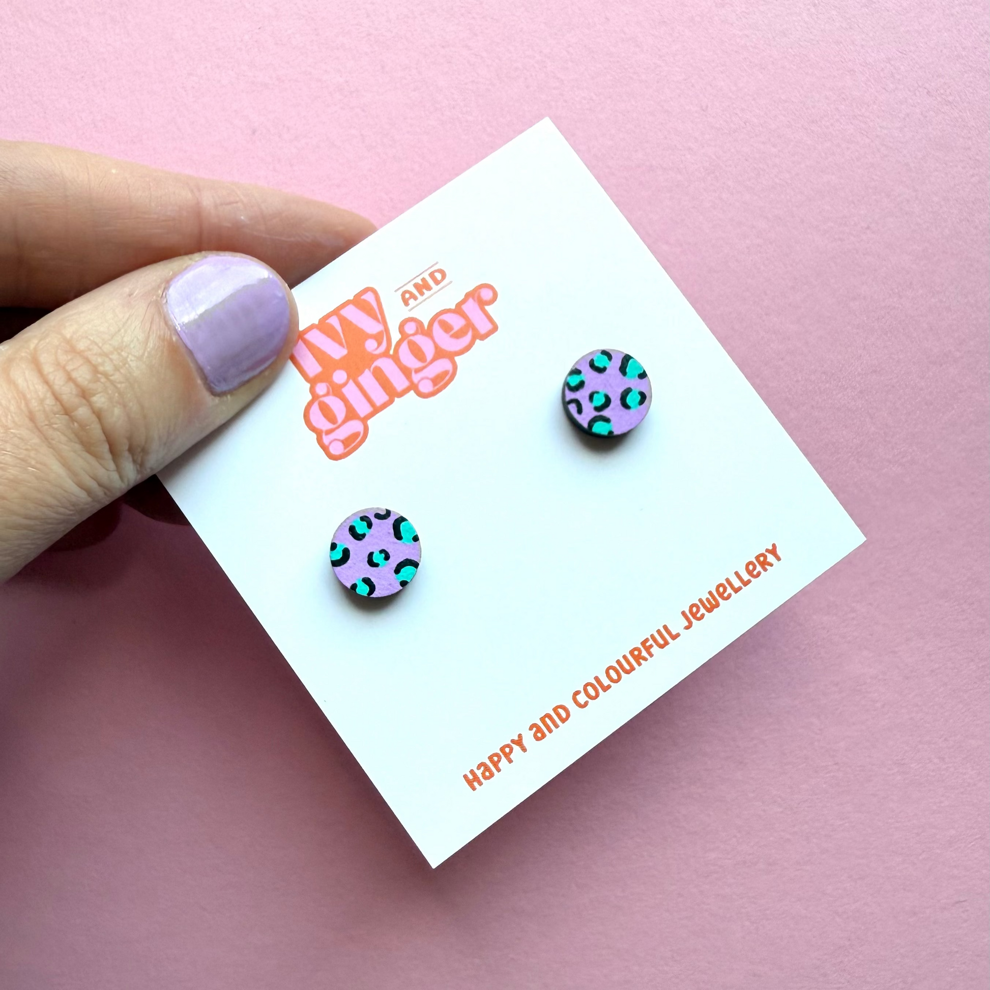 Hand holding a card with colorful earrings and 'My Ginger' branding on a pink background