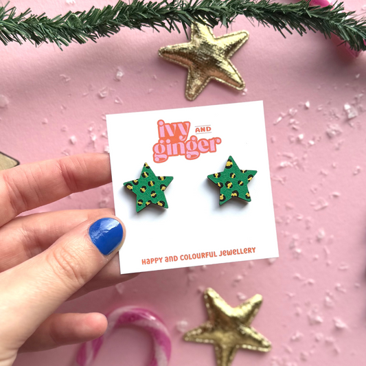 Star-shaped earrings on a 'ivy and ginger' card against a festive pink background with candy canes and gold stars.