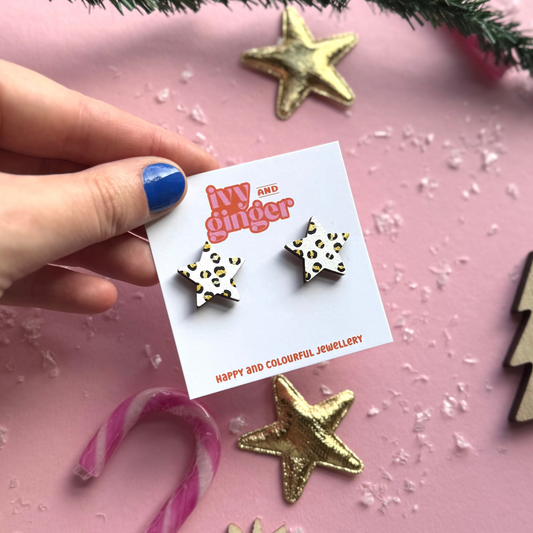 Star-shaped earrings on a branded card with decorative items in the background